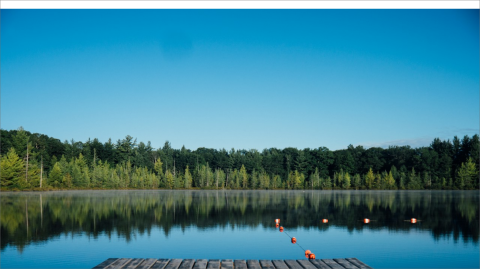 A photo of a peaceful lake surrounded by evergreen trees.